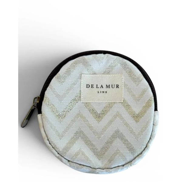 Monedero Redondo Astro De La Mur con estampado tipo zigzag y lurex dorado sobre fondo crudo.